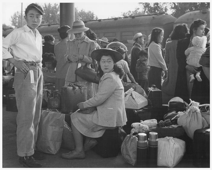 Families of Japanese ancestry awaiting a train which will take them to the Merced Assembly Center